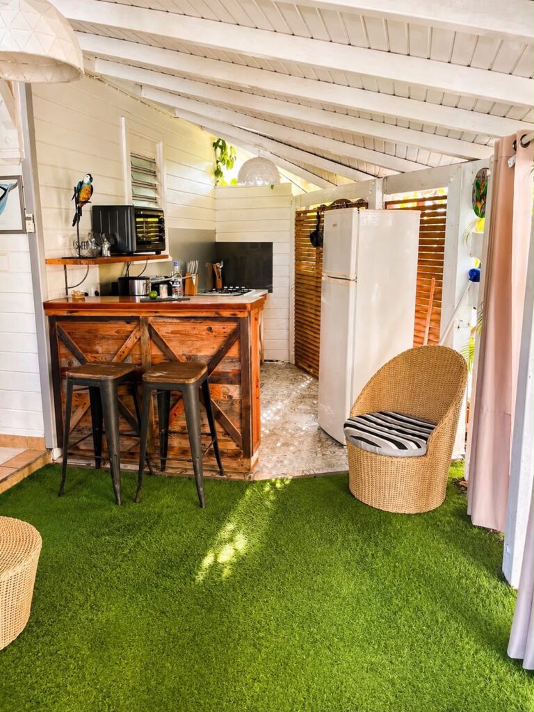 Coin bar extérieur convivial avec tabourets et salon en osier, sur la terrasse en gazon du gîte Bois Patate, Les Bois d'Orée