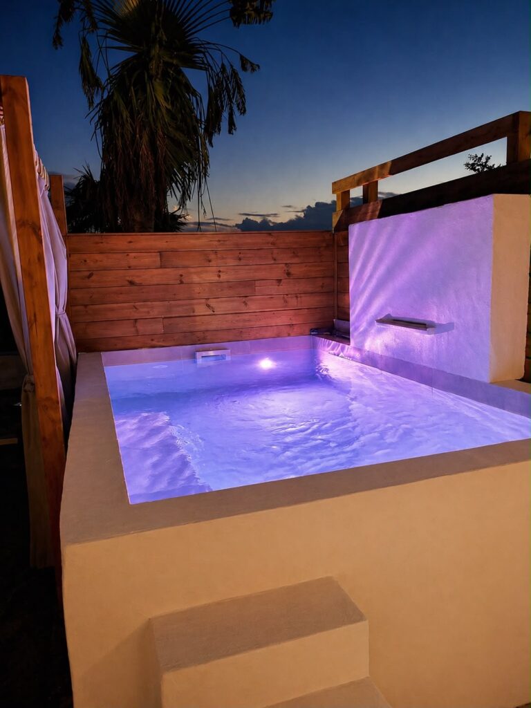 Jacuzzi privatif illuminé en soirée avec vue sur les palmiers du gîte Bois Savon, Les Bois d'Orée