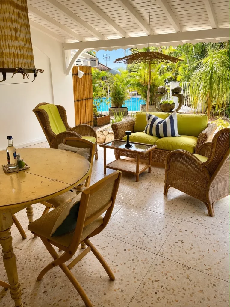 Vue de la terrasse privative du gîte Bois Banane avec salon en rotin, table à manger et vue sur la piscine et le jardin tropical, Les Bois d'Orée
